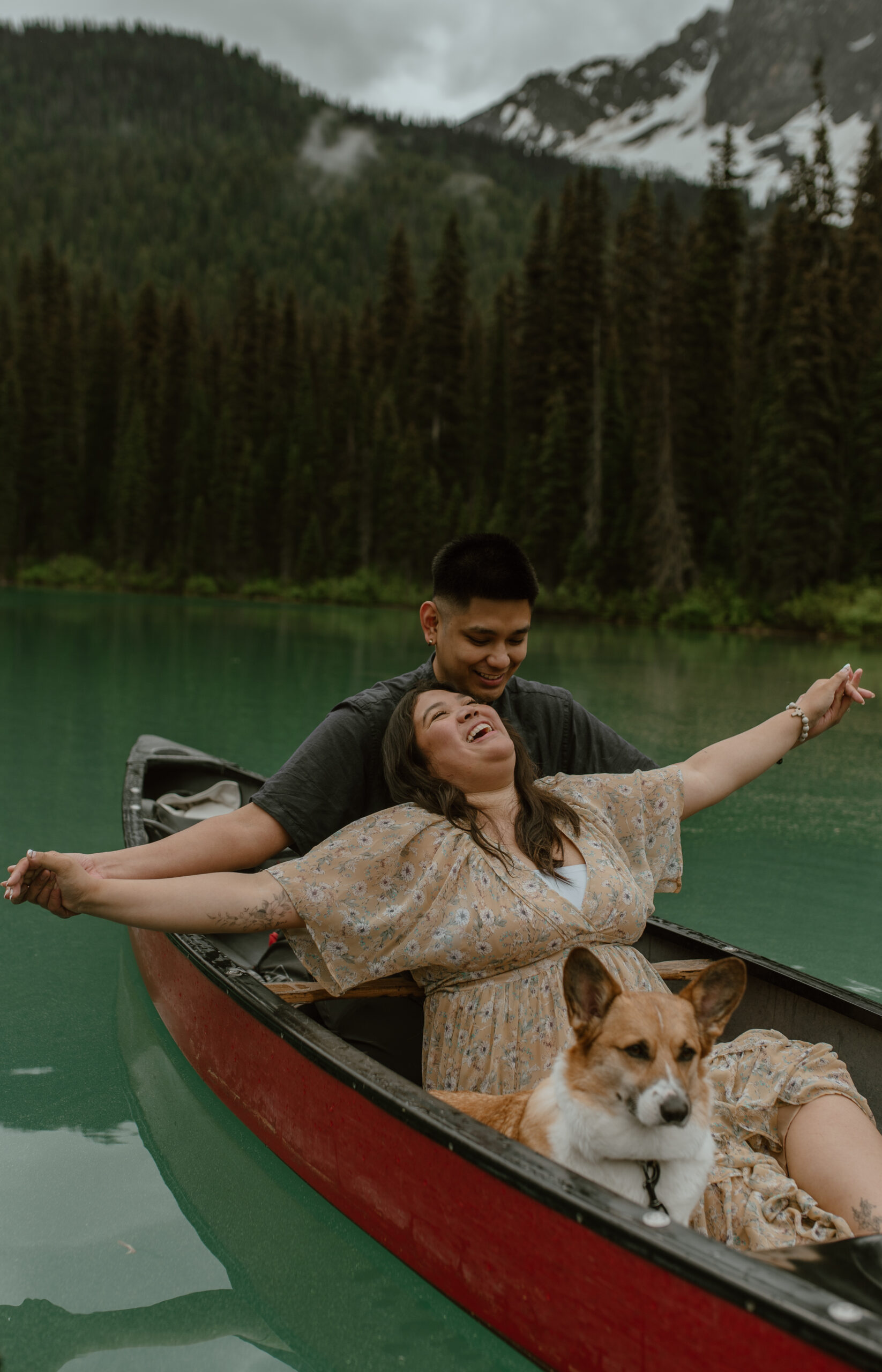 candid laughing shot of couple enjoying the rain during their canoeing engagement session in Banff, Canada