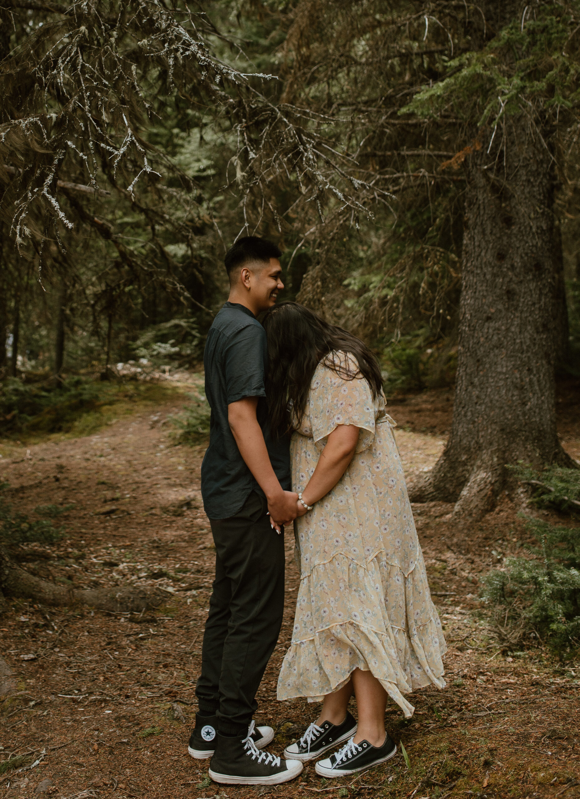 couple laughing in forest during an engagement session in Banff, Alberta