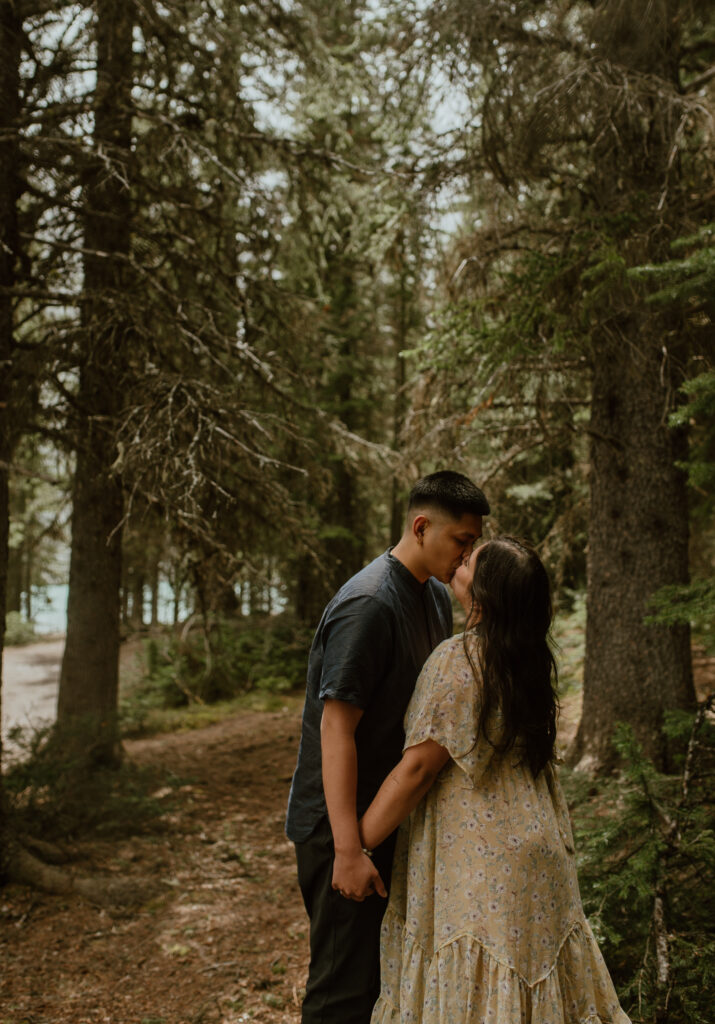 couple kissing in forest in national park in Alberta, Canada