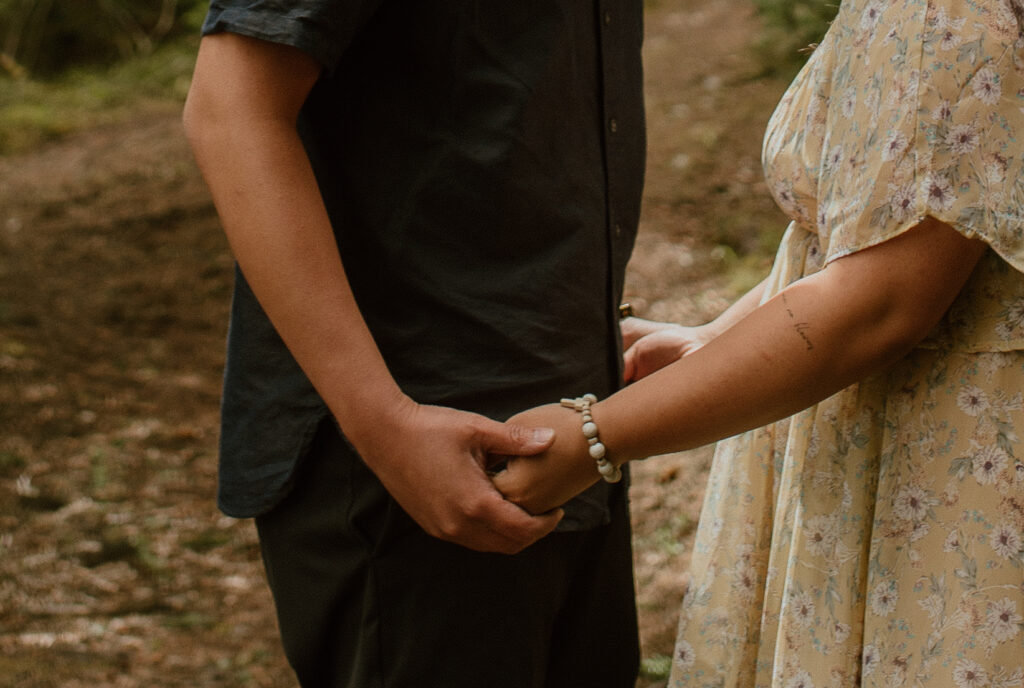 hand holding in forest during an adventure engagement session in Banff, Alberta