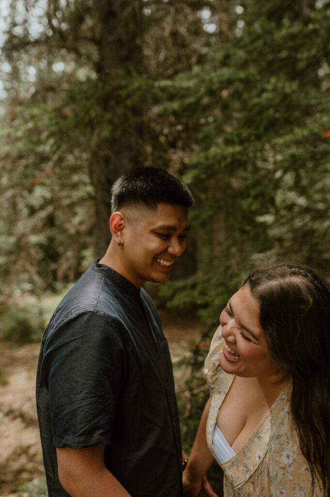 candid couple laughing together during engagement session in Banff, Canada