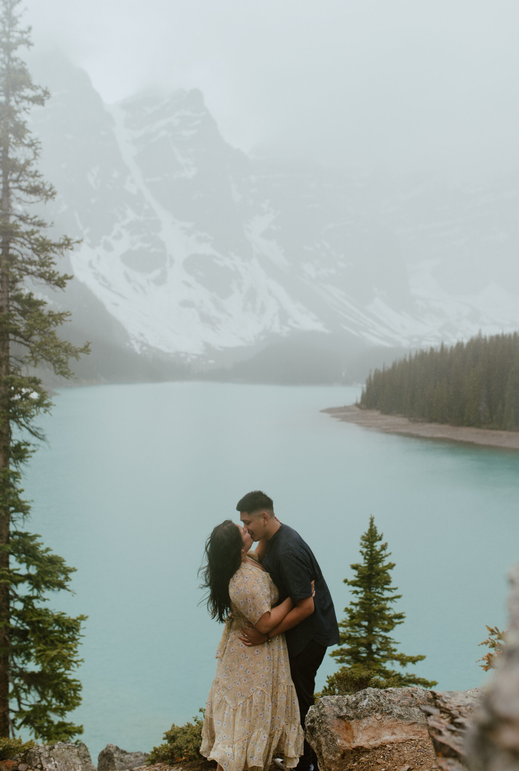 dramatic kissing shot in the rain in front of Moraine Lake, Alberta