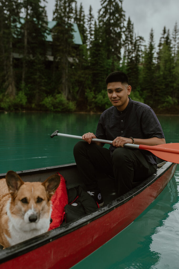 man with dog enjoying rainy canoe ride on Emerald Lake, Canada