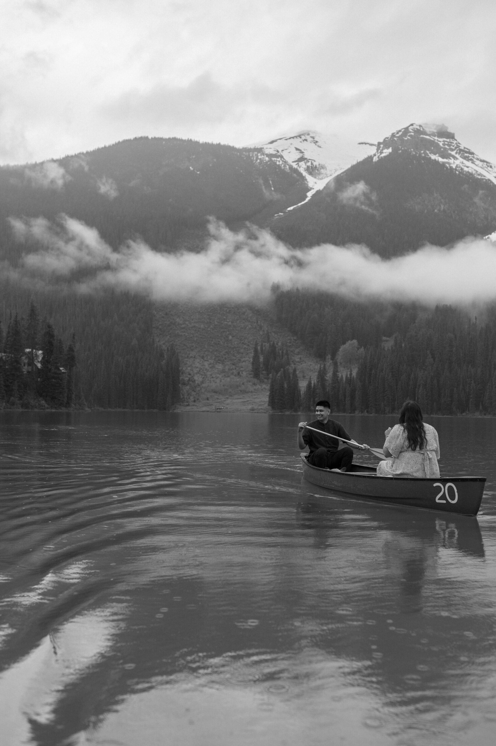 black and white photo of couple canoeing on mountain lake in Canada