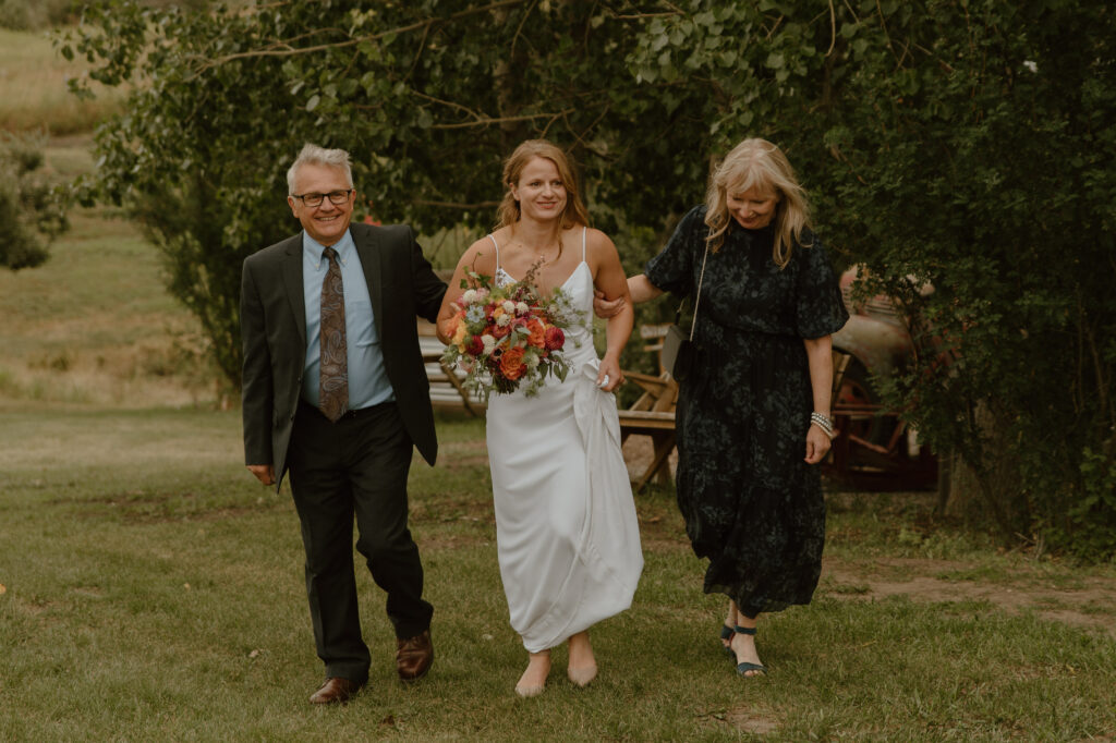 bride being walked up wedding aisle with parents in Longview, Alberta