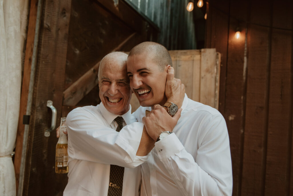father and son sharing embrace during summer wedding in British Columbia, Canada