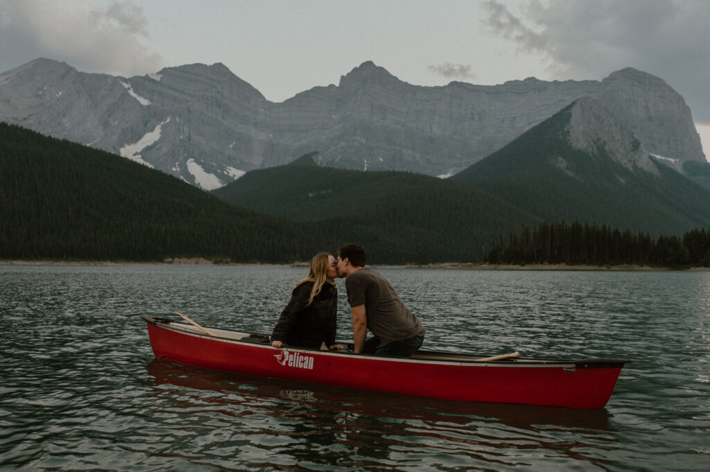 couple sharing kiss in canoe while canoeing on mountain lake in Kananaskis, Alberta