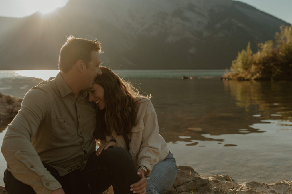 couple sharing intimate moment during sunrise at Lake Minnewanka in Banff for a proposal