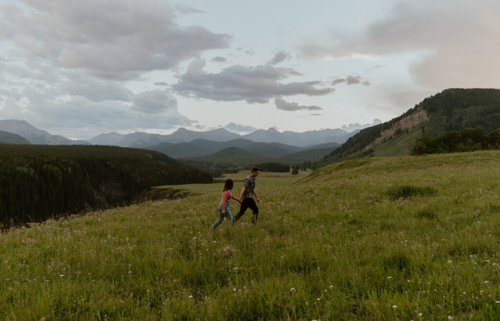 couple walking through wildflower field in Alberta, Canada for anniversary session