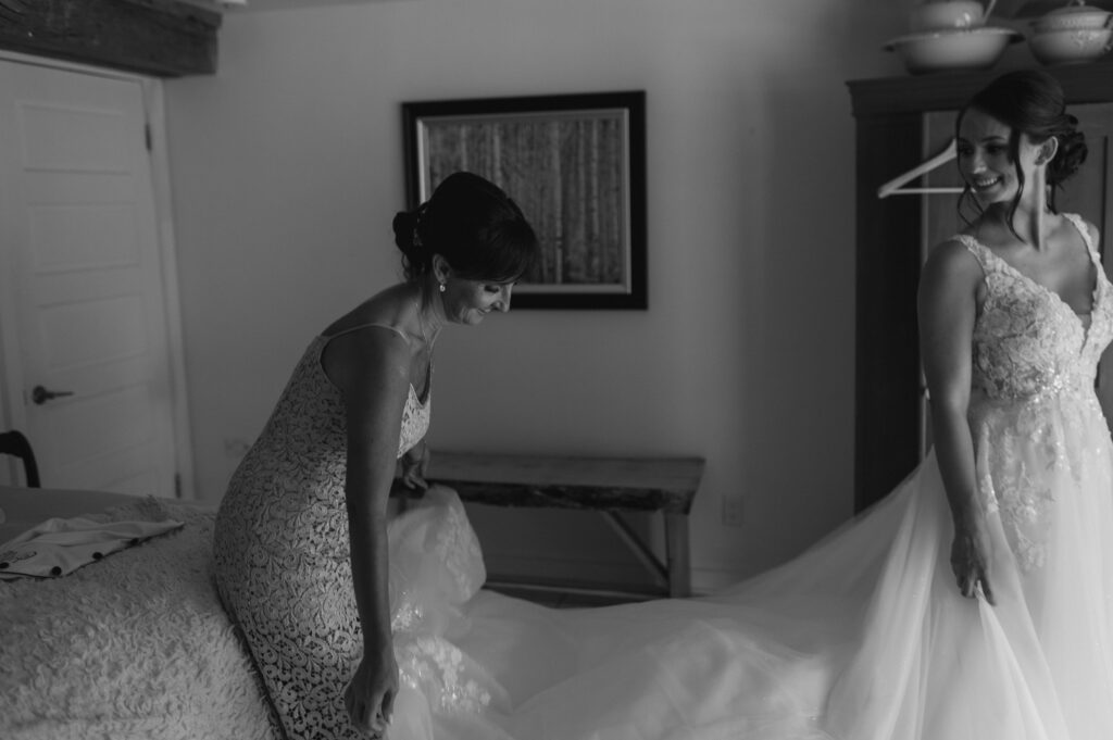 mother helping daughter with wedding dress during a southern ontario summer wedding