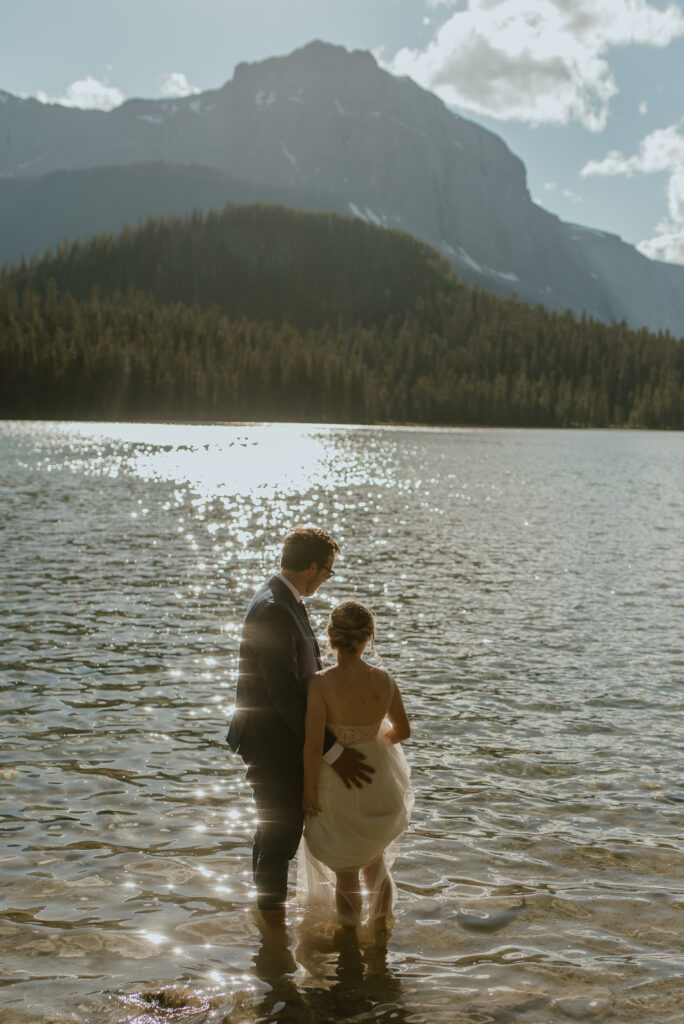 couple enjoying mountain lake in wedding attire after their elopement in Canmore, Canada