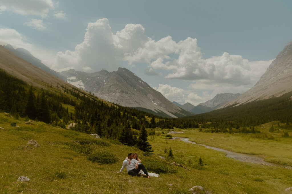 couple laying in mountain meadow for their elopement by alberta adventure wedding photographer sun peak photo